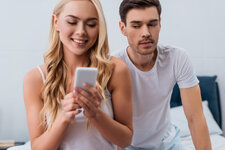 jealous-man-looking-at-beautiful-smiling-wife-usin-2022-02-03-20-41-31-utc-1400x934.jpg