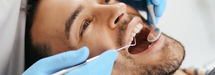 smiling-young-man-sitting-dentist-chair-while-doctor-examining-his-teeth_31-1210x423.jpeg